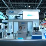 Trade show booth for Slee with blue and white branding, reception desk, and product displays at a convention center.